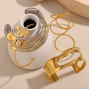 Close-up of gold and silver four-leaf clover bracelet with sleek layered gold rings