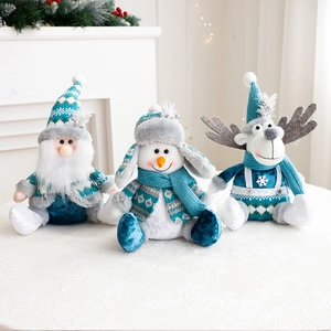 Three plush Christmas dolls in blue and gray sitting on a white patterned tablecloth