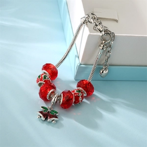 Christmas charm bracelet with red beads and silver bell pendant on a gift box