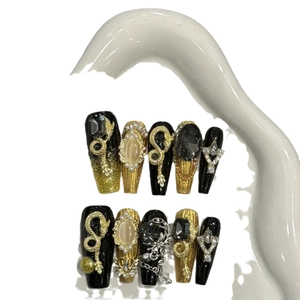 Handmade black and gold cat eye press-on nails with 3D snake and rhinestone charms