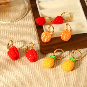 Detailed close-up of fruit-themed gold hoop earrings with strawberry and pineapple charms