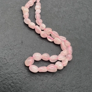 Detailed macro view of natural polished rose quartz stones on a durable stainless steel chain