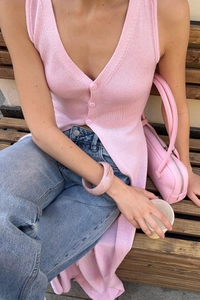 Detail of pink knitted long vest with V-neck buttons and soft textured fabric