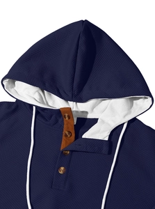 Détail du sweat à capuche bleu marine en tissu gaufré avec boutons en bois et cordon blanc