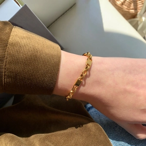 Gros plan d'un bracelet chaîne plaqué or 18k avec breloque rectangulaire au poignet