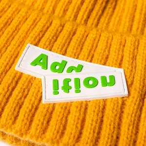 Knitted mustard yellow beanie featuring a 3D ribbed texture and green lettered rubber patch