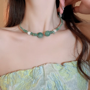 Dettaglio della collana di perline verdi con pietre naturali e accenti floreali
