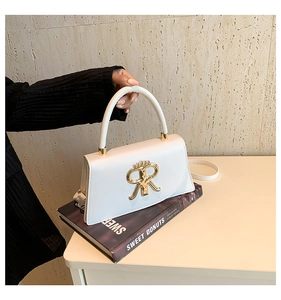 Detail of white leather trapezoid handbag with gold RR logo on a fashion magazine