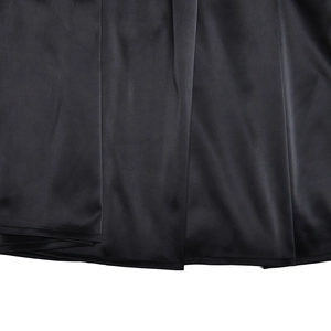 Detail showing the elegant drape and glossy texture of the black silk fabric dress