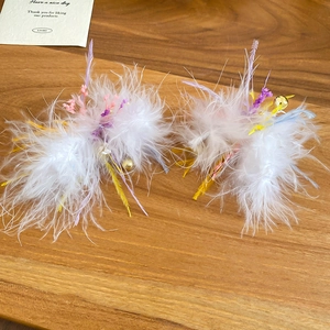 Detailed macro view of white feathers with purple flowers and golden bell charms