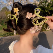 Detail view of flower-shaped hair claws with pink and yellow petals on gold metal frame