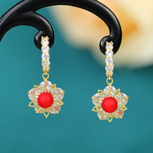 Macro detail of gold flower earring with red bead and clear cubic zirconia stones