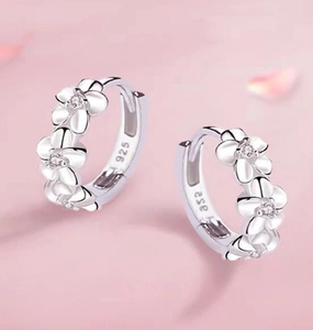 Macro detail of 925 sterling silver hoop earrings with floral relief and zircon stones