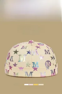 Gros plan du bonnet docker beige avec logos M métalliques colorés et motifs d'étoiles