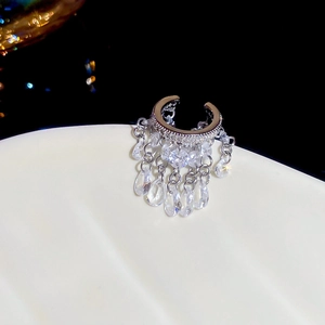 Gros plan sur un earcuff en C argenté avec des glands en cristal et pendentifs gouttes