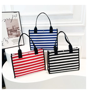 Detailed display of striped canvas tote bags in blue, red, and black with button closure
