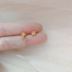 Detailed view of asymmetric gold flower earrings with zircon inlays on fingertips