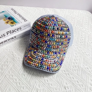 Close-up of colorful faux pearls and silver studs on a stylish light blue baseball cap