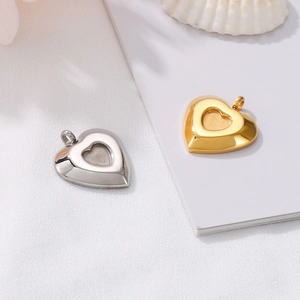 Polished gold and silver heart-shaped locket pendants on a minimalist white background