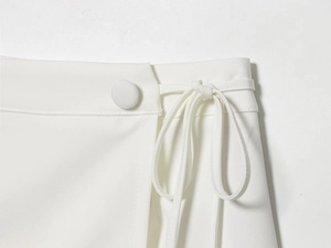Detail view of a white mini skirt waist with a side button and elegant tie-waist cord
