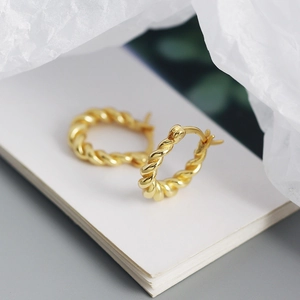 Macro shot of gold twist texture U-shaped hoop earrings with elegant polished finish