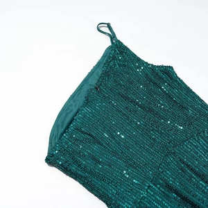 Detailed view of dark green sequin texture and strap design on a long split dress