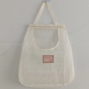 Hanging white mesh storage bag for ginger and garlic with a decorative leather patch