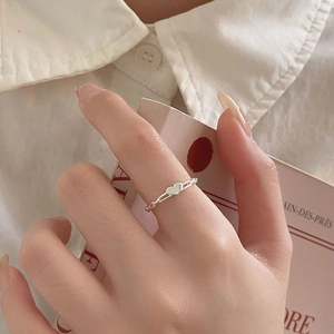 Detail of 925 sterling silver heart ring with woven chain band on finger