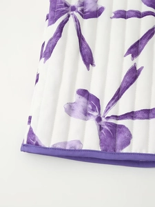 Detailed close-up of quilted cotton fabric with purple bow patterns and piped edge