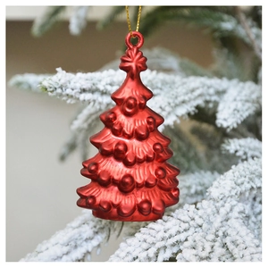 Close-up of a festive red Christmas tree ornament hanging on a snow-covered pine branch