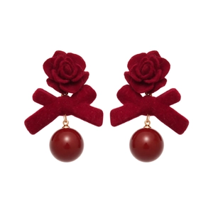Boucles d'oreilles rose en velours rouge avec nœud et perle polie sur fond blanc pur