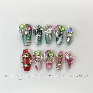 Detail of handmade Christmas press-on nails with 3D rhinestones and pearls on red and green