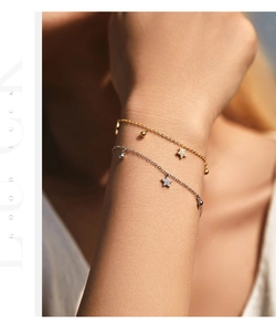 Detail of gold and silver S925 sterling silver bracelets with star pendants on wrist