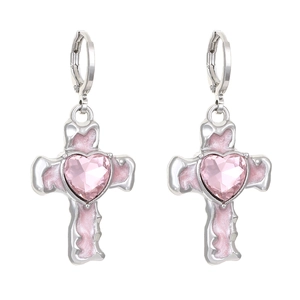 Macro detail of silver cross earrings with pink heart crystal and glitter enamel
