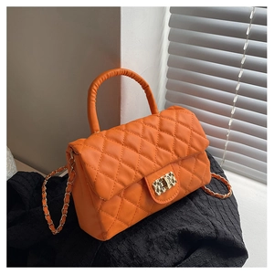 Detail view of orange quilted leather handbag featuring a gold chain and metal lock