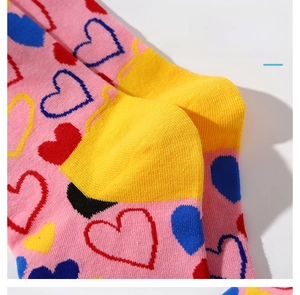 Détail d'une chaussette en coton rose avec cœurs colorés et talon antidérapant jaune