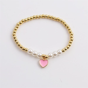 Detail of beaded bracelet with gold copper beads, white pearls, and pink enamel heart charm