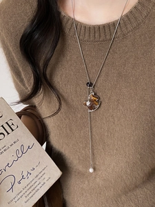 Detailed macro view of a vintage resin bear pendant and pearl drop on a silver necklace