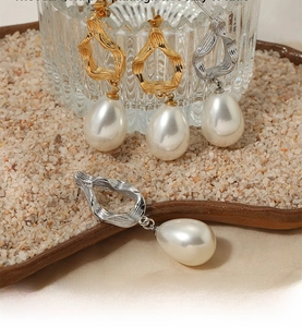 Detailed shot of gold and silver irregular wave earrings with large drop pearls in a tray