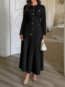 Detail of elegant black knit maxi dress with gold buttons and textured finish
