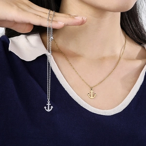 Detailed comparison of gold and silver anchor necklaces worn for fashion display