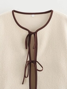 Détail de la veste polaire crème montrant les liens marrons et la texture douce