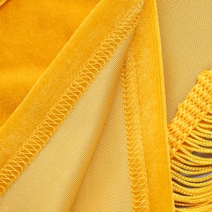 Détail macro du tissu en velours jaune vif avec coutures fines et bord à franges