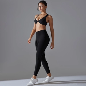 Detail of high-waist yoga set with cross-front sports bra in black elastic fabric