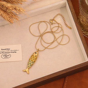 Detailed macro of golden koi fish pendant with green enamel on a snake bone chain