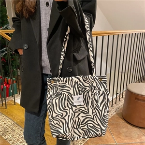 Zebra print corduroy tote bag shown on model in cozy home setting with woven label
