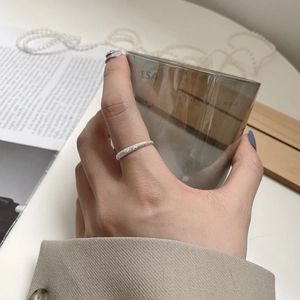 Detail shot of a shimmering silver ring with frosted texture worn on finger
