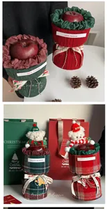 Close-up of Christmas apple gift wrap with tweed fabric, plush bear, and decorative ribbon