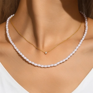 Close-up of elegant double-layered gold necklace with zircon pendant and pearls on neck