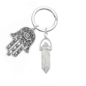 Detail of Hamsa hand evil eye charm with white marble hexagonal crystal on silver keychain